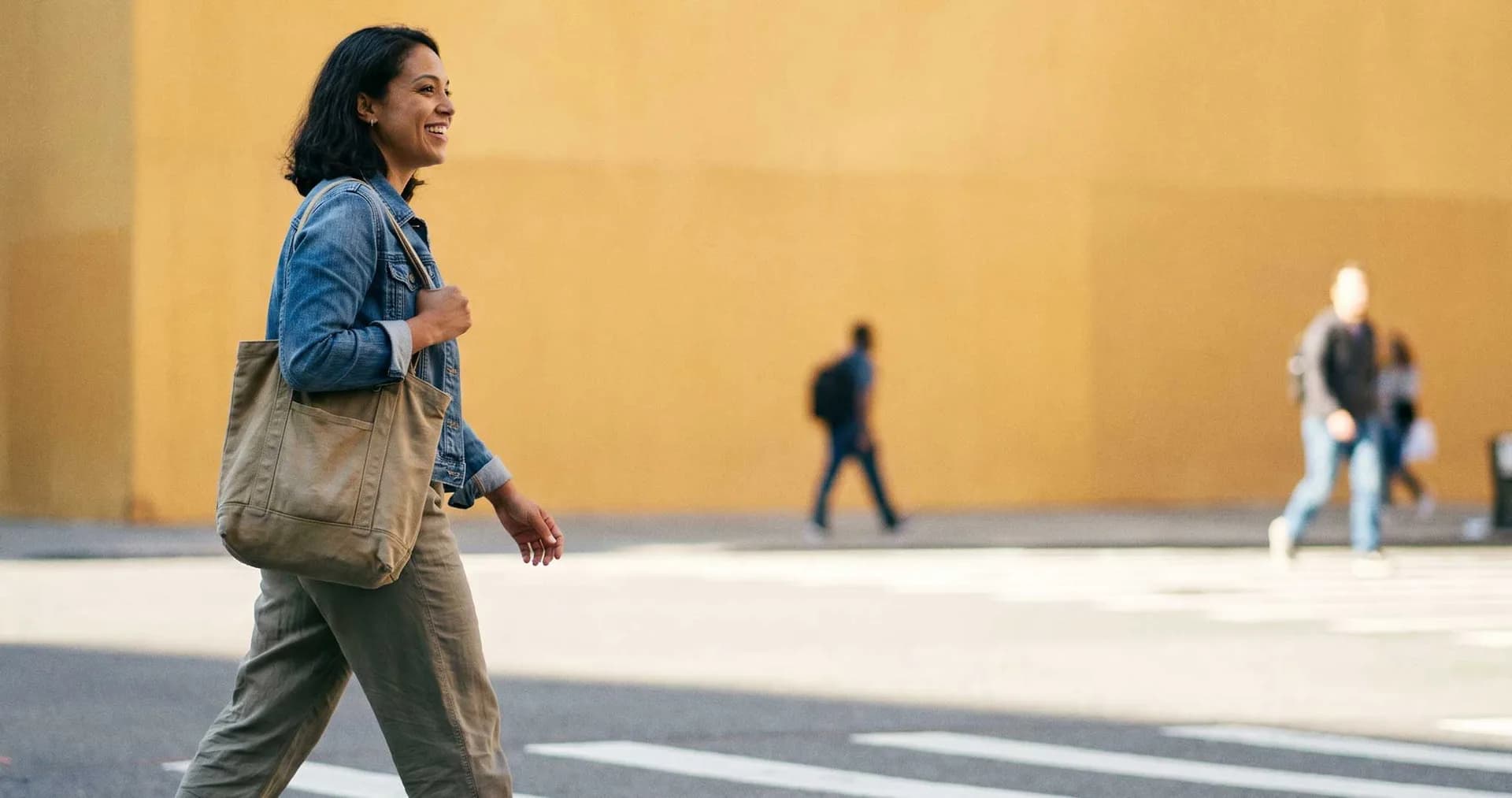 Woman smiling as she walks across a city street